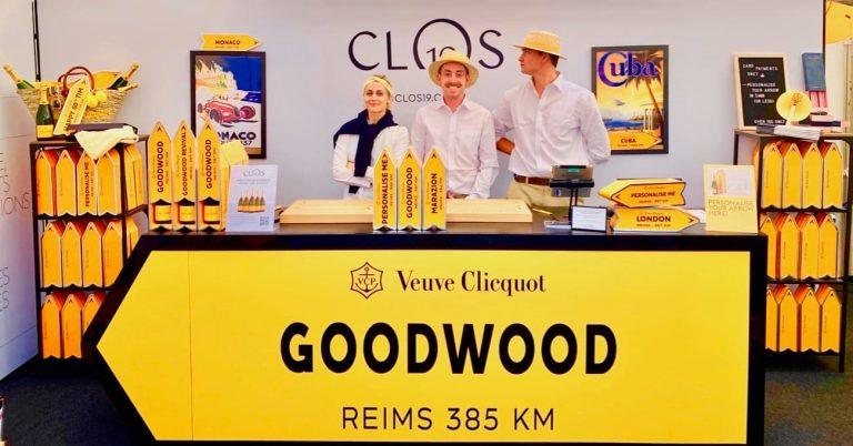 Veuve Clicquot Yellow Desk at Goodwood Revival with three people stood behind wearing hats