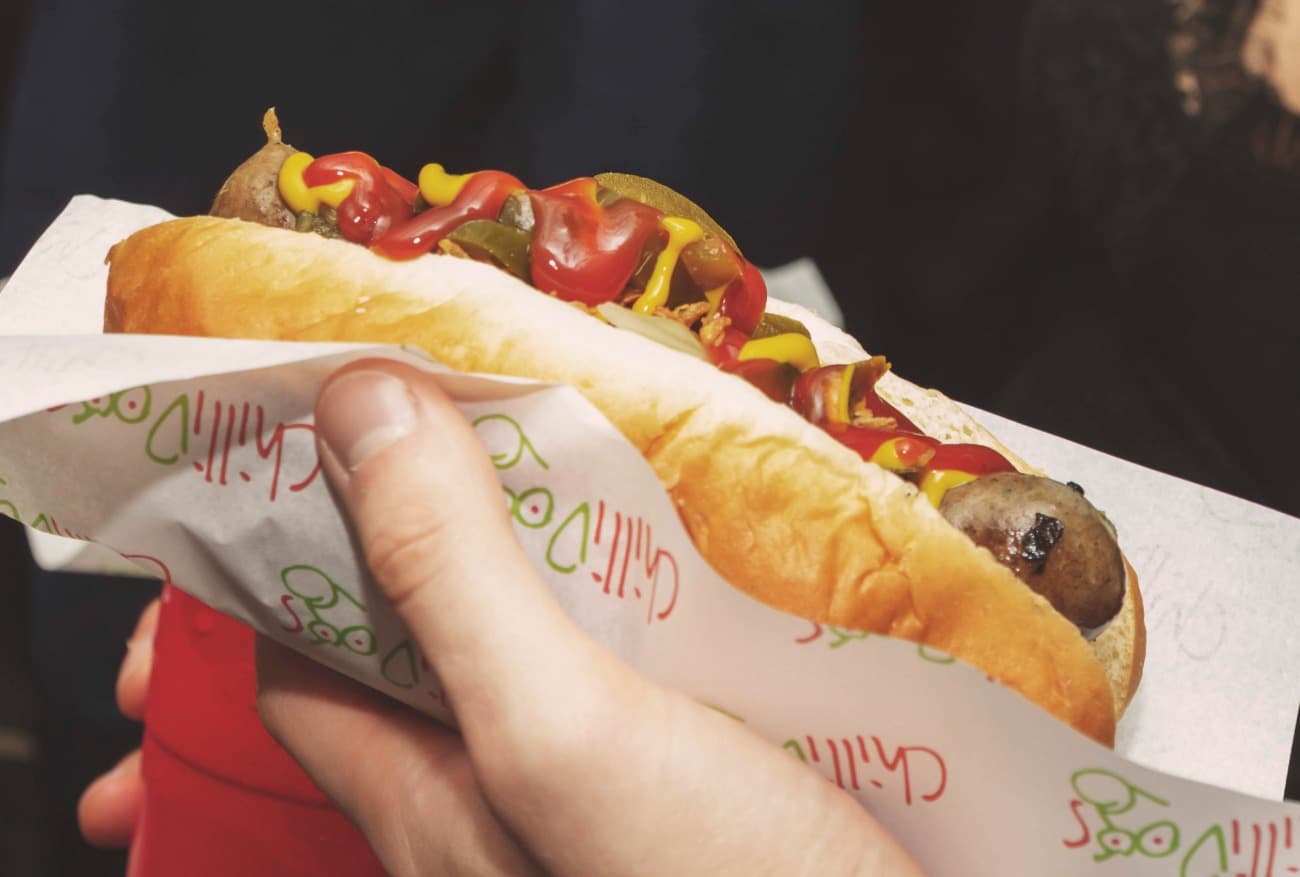 Chilli hot dog held in hand with mustard