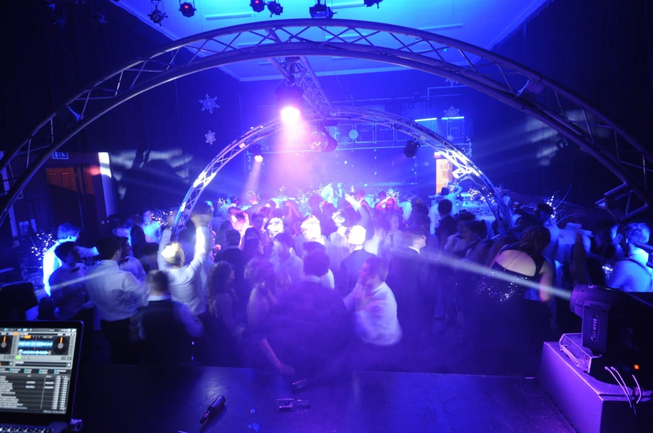 Packed dance floor under a mobile nightclub lighting rig with moving beams of light