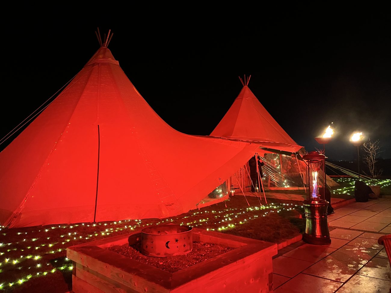 Game of Thrones Themed Party in Giant Tipi Marquees. Two giant tipis at night lit in red and green on a lawn