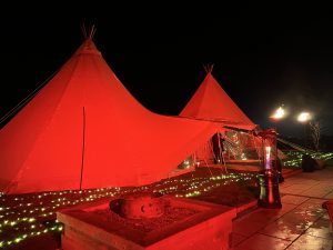 Natasha 6 Game of Thrones Themed Party in Giant Tipis. Two giant tipis at night lit in red and green on a lawn
