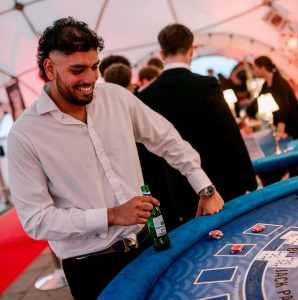 DSC_0171 A young man smiles while playing black jack at a casino themed party
