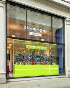 The front of the corner shop at Selfridges, Oxford Street set up with basketball jerseys to personalise NBA jerseys for Hennessy. The words "custom bar" sit above 5 personalised jerseys.
