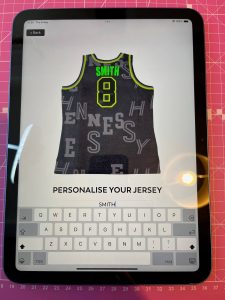 An ipad showing a picture of an NBA basketball jersey, personalised with the word "Smith."