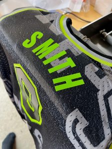 An NBA basketball jersey on a heat press, personalised with the word "Smith."
