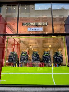 The front of the corner shop at Selfridges, Oxford Street set up with basketball jerseys to personalise NBA jerseys for Hennessy. The words "custom bar" sit above 5 personalised jerseys.