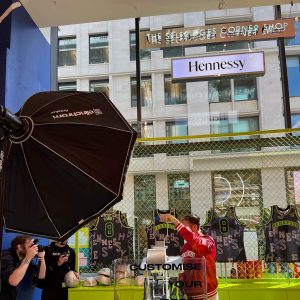 A model having his photo taken while personalising NBA jerseys with a heat pres for Hennessy.