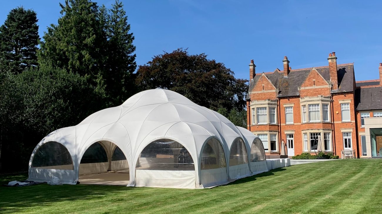 Dome marquee on a grass lawn outside a red brick house
